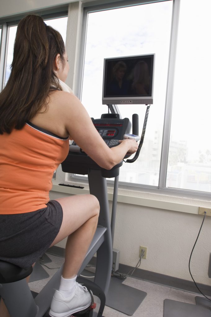 Woman Exercising on a Stationary Bike with a TV